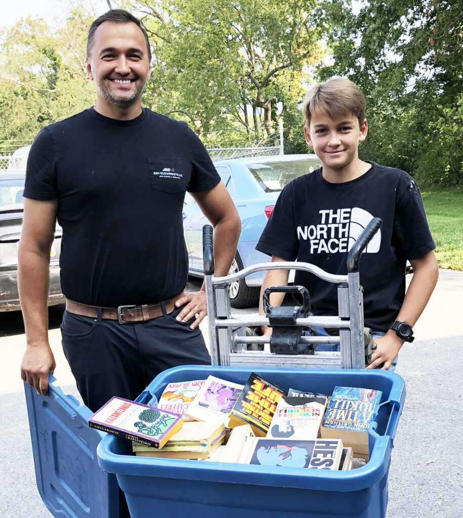 Book donors carrying tubs of donations